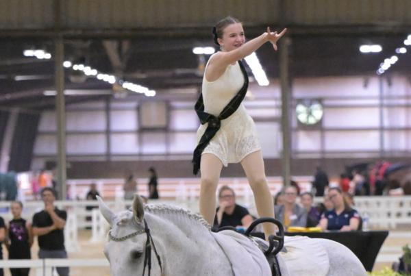iSVA's Gracelyn Rogers competes in equestrian National Championship; pictured riding a horse and pointing at the crowd